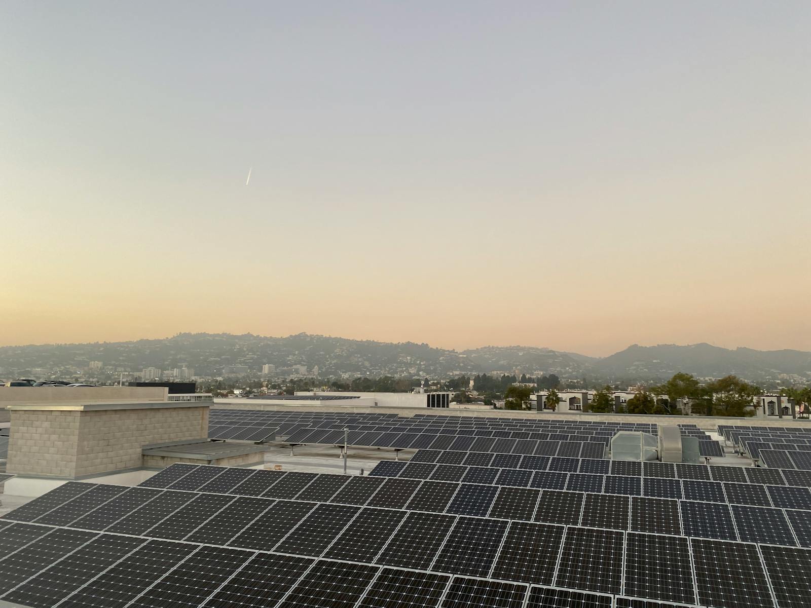 Installation de panneaux solaires sur toit-terrasse au coucher du soleil, collines en arrière-plan